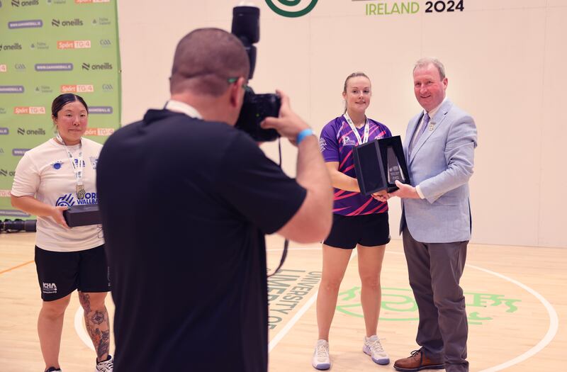 GAA handball president Conor McDonnell presents a trophy to Martina McMahon, Limerick winner of ladies' small ball final, watched by runner-up Myohwa Hwee, USA