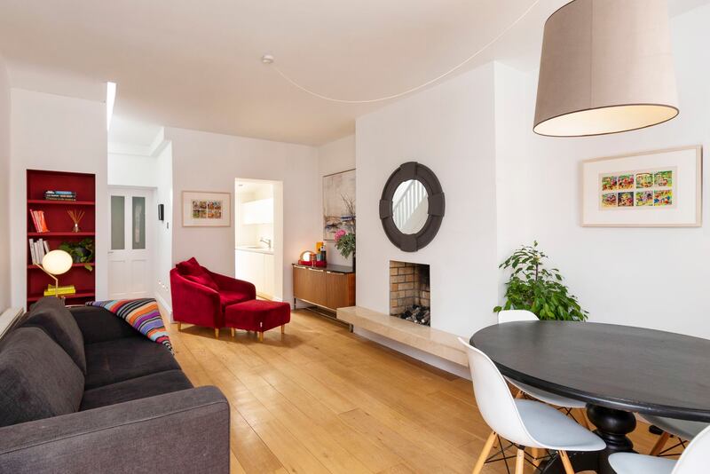Higgins added solid oak floors and a Crema Marfil hearth to the livingroom. A long flex allows her to move the single ceiling light around the room
