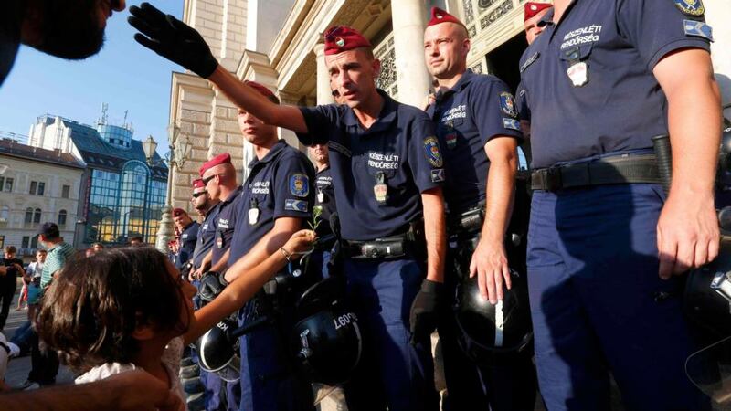 A young girl offers a flower as a man talks to a police officer during a demonstration by migrants outside Keleti railway station in Budapest on Tuesday. Photograph: Laszlo Balogh/Reuters