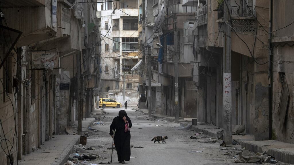 A woman walks down a street in Ariha, in Idlib Province, Syria, on March 12th. Ariha is mostly deserted, the smashed buildings and shrapnel scars on walls clear signs of the heavy aerial bombardment and artillery fire over the last several weeks. Photograph: Tyler Hicks/The New York Times