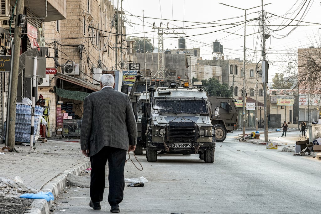 A man walks by as Israeli army vehicles pass in the Palestinian village of Qabatiyah. Photograph: Jaafar Ashtiyeh/AFP