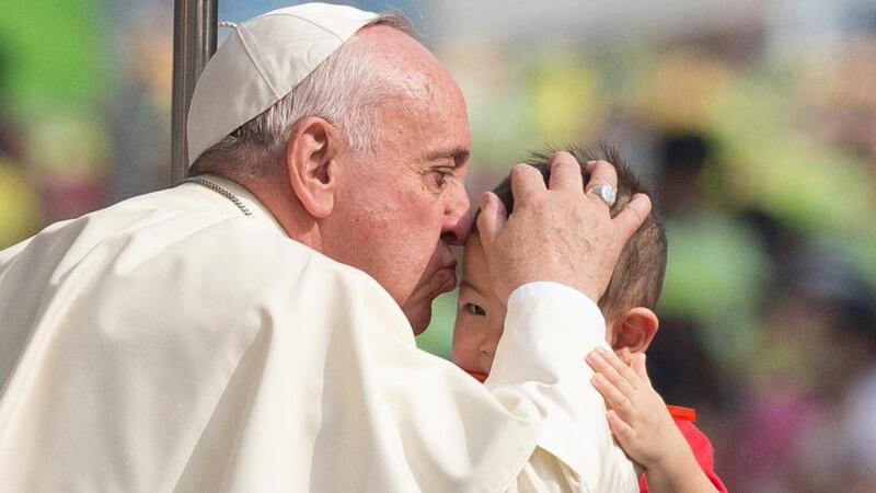 Pope Francis kisses a child as he greets Catholic faithful from his Popemobile upon arriving for Holy Mass in Seoul. Photograph: EPA
