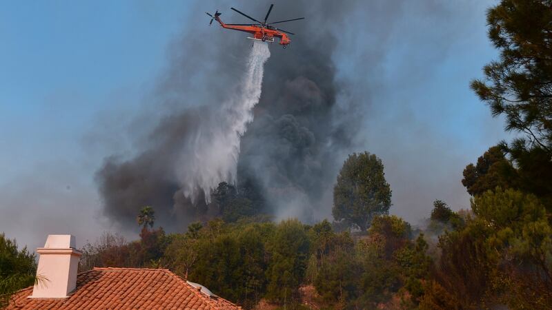 A helicopter drops water over a house on the hilltop in Bel Air, Los Angeles, California. Photograph: FREDERIC J. BROWN/AFP/Getty Images