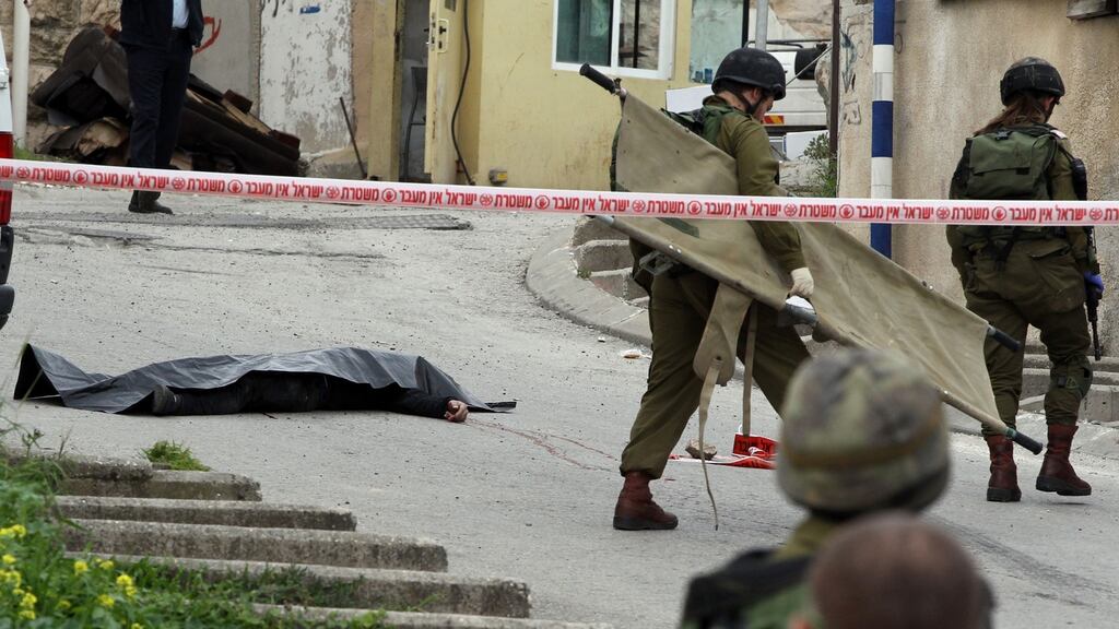 Israeli soldiers prepare to remove the body of the Palestinian assailant in Hebron last Thursday. Photograph: Hazem Bader/AFP/Getty Images