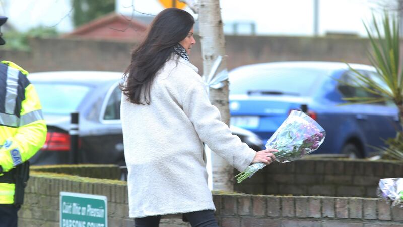 A woman leaves flowers outside the house in Parson’s Court in Newcastle in which the bodies of three children were found. Photograph: Collins
