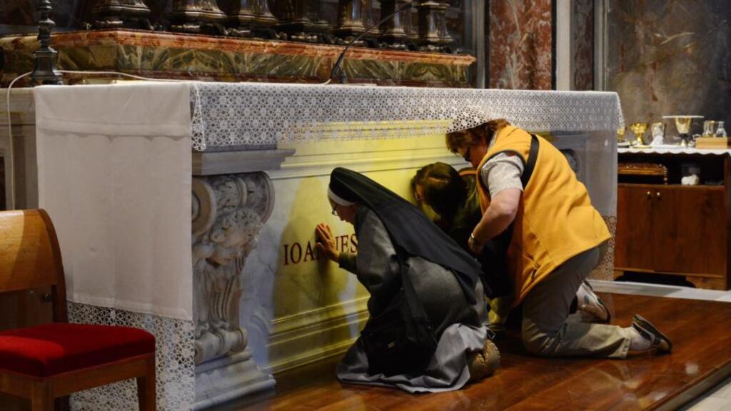 Pilgrims pray at the grave of pope John Paul II in the St Sebastian Chapel of St Peter’s Basilica. Up to 1 million pilgrims and tourists from all over the world are expected in Rome this weekend for the historic double canonization of Pope John Paul and Pope John XXIII. Photograph: Radek Pietruszka/EPA