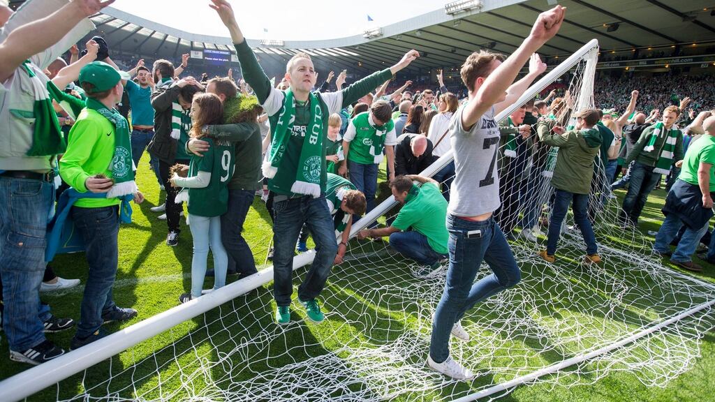 Hibernian fans celebrate on the pitch after beating Rangers in the Scottish Cup Final. Photo: Jeff Holmes/PA Wire