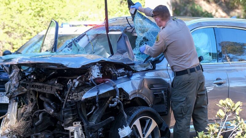 Am officer looks over the damaged vehicle Woods was travelling in. Photo: Ringo H.W. Chiu/AP Photo