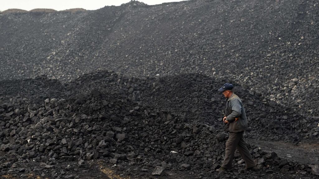 A worker walks past a pile of coal near a coal mine in China. Photograph: Greg Baker/AFP/Getty Images