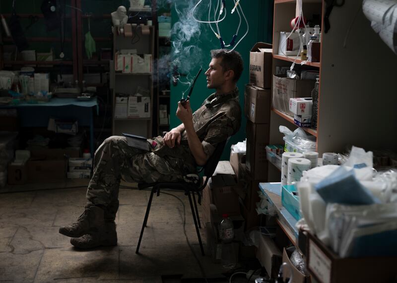Romashka, the head of a medical stabilisation point in the Zaporizhzhia region of Ukraine, smoking a pipe after finishing treating patients. Photograph: Emile Ducke/The New York Times