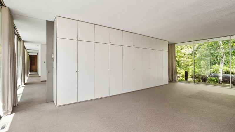Main bedroom with windows on two sides and built-in wardrobes forming dividing wall.