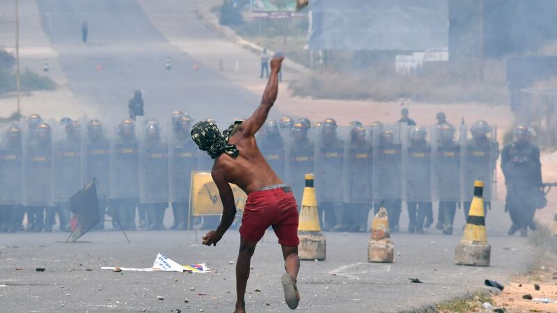 Demonstrators throw stones at Venezuelan Bolivarian National Guard members standing guard in the Venezuela-Brazil border, in Pacaraima, Roraima state, Brazil. Photograph: Nelson Almeida/AFP/Getty Images