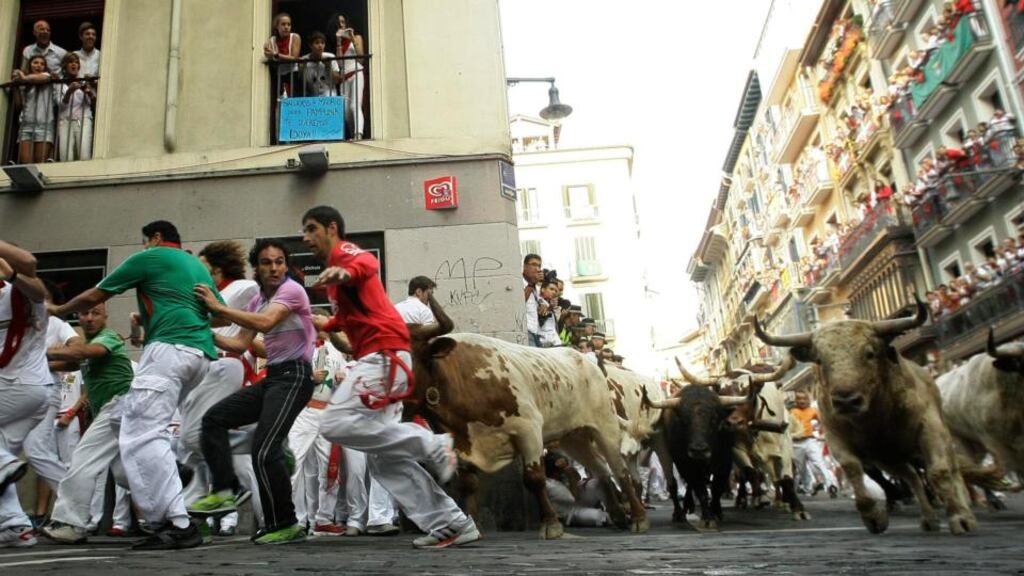 Runners sprint alongside Torrestrella fighting bulls as they take the Estafeta curve during the fifth running of the bulls of the San Fermin festival in Pamplona. Photograph: Susana Vera/Reuters