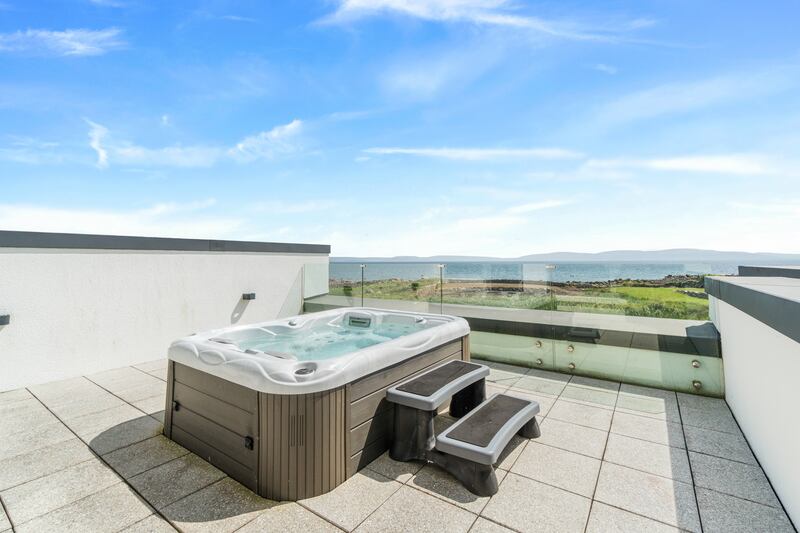 A hot tub lies on an upper terrace with great sea views