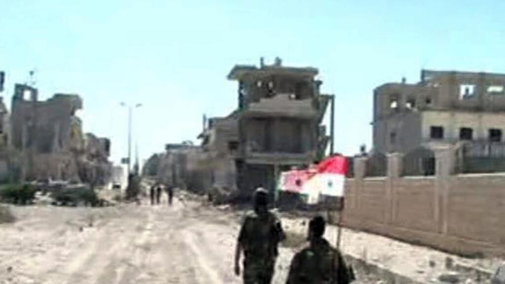 Forces loyal to Syria’s president Bashar al-Assad carry their national flag as they walk along a street in Qusair. Photograph: Reuters