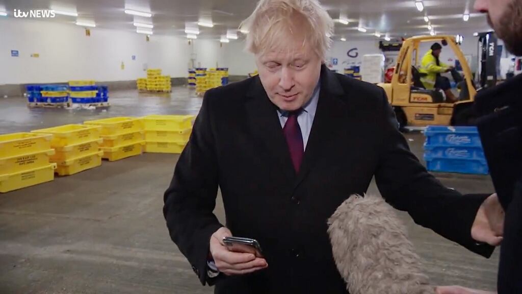 British prime minister Boris Johnson looks at the photograph on ITV reporter Joe Pike’s phone of four-year-old Jack Williment-Barr lying on  the floor of the emergency department at Leeds General Hospital, after initially refusing to look at it. Screen grab: ITV/PA Wire