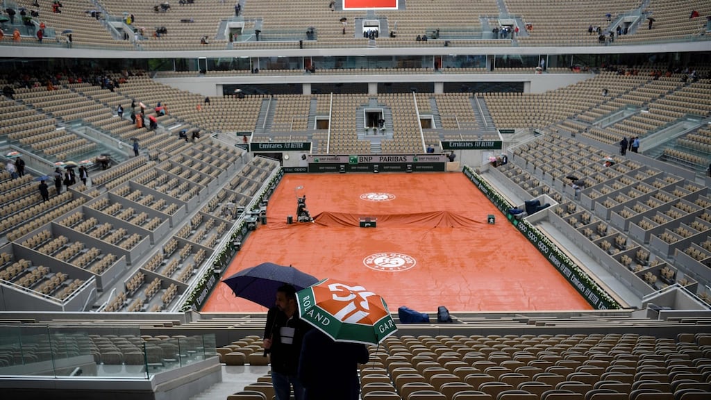 People hold their umbrella in the empty stands as rain falls on Wednesday at the Roland Garros 2019 French Open. Photo: Christophe Archambault/Getty Images