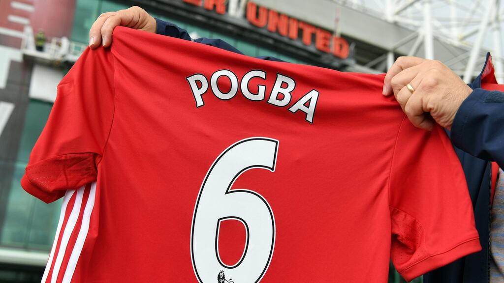 A man poses for pictures after purchasing a Manchester United shirt with the name and squad number of recent signing French midfielder Paul Pogba outside Old Traford. The world record for a transfer fee was shredded Tuesday when French superstar Paul Pogba completed a sensational return to Manchester United from Juventus for €105 million euros. Photo: Getty Images