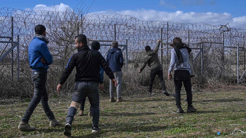 Migrants stand near the border fence on the Turkey-Greece border buffer zone Photograph: Ozan Kose/AFP/ Getty Images