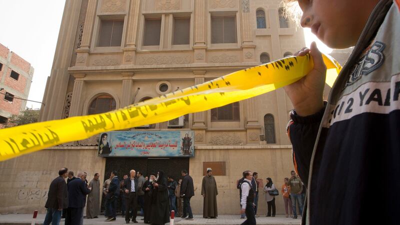 A boy holds the yellow label surrounding the site in front of Mar Mina church, in Helwan, Cairo, Egypt. Photograph: (AP Photo/Amr Nabil