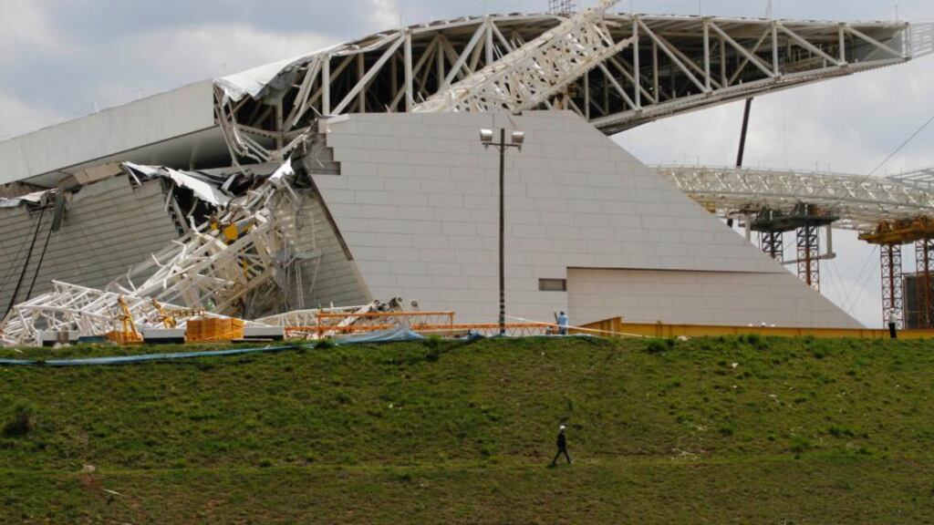 Workers stand near a crane that collapsed on the site of the Arena Sao Paulo stadium, known also as “Itaquerao do Corinthians”, which will host the opening match of the 2014 World Cup. Photograph: Nacho Doce/Reuters