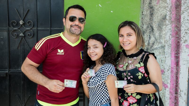 Roberto Rincon, Anggy Garcia and Victoria Donquiz (12) are pictured after receiving their permits to live and work in Peru. Photograph: Paul Musiol