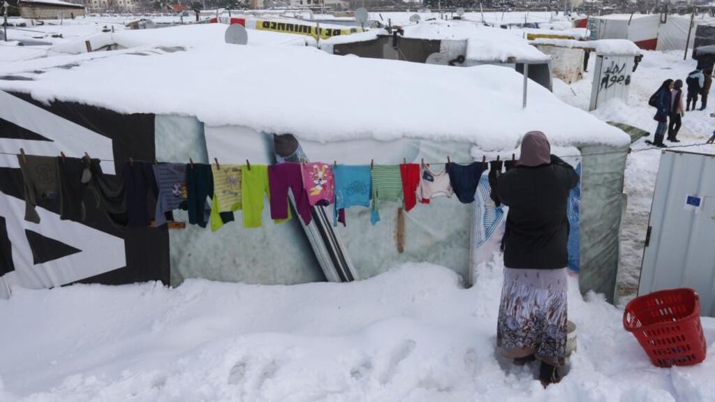 A Syrian woman hangs her laundry outside a tent  at a refugee camp in Zahleh town, Bekaa valley, east Lebanon. Heavy snow fell in the Middle East as a winter storm swept through the region. Photograph: Hussein Mallay/AP