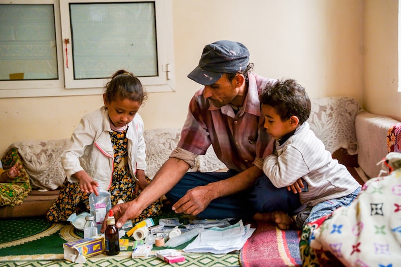 Nabil sits with Mohammed and with the various boxes of medicines to treat his cholera. Photograph: Alsunaidar/Unicef, Yemen, 2023