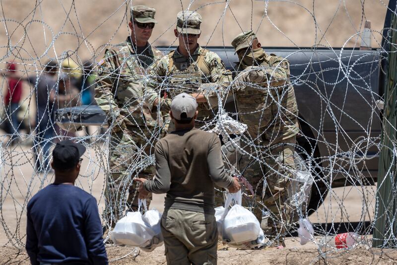 Texas National Guard soldiers close a section of razor wire surrounding a makeshift migrant camp as an immigrant tries to return with food for his family in El Paso, Texas. Photograph: John Moore/Getty Images