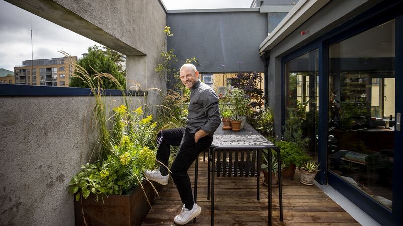 Mark Grehan in his garden. The terrace’s outer concrete boundary walls are painted a warm shade of charcoal-grey that mirrors the interior walls of his apartment. Photograph: Tom Honan