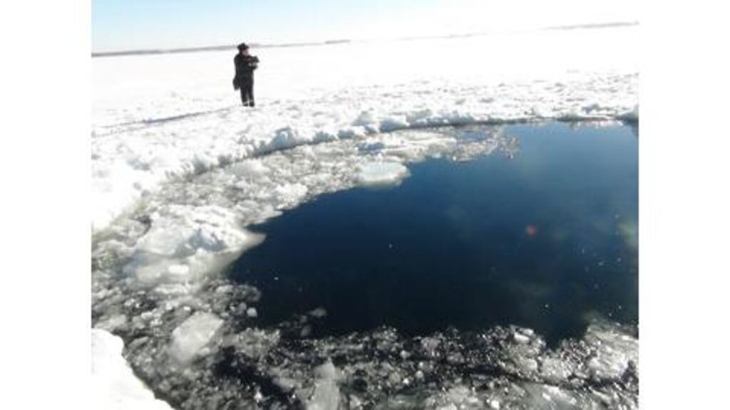 A Russian policeman works near an ice hole, said to be the point of impact of a meteor seen earlier in the Urals region, at lake Chebarkul yesterday. Photograph: Reuters