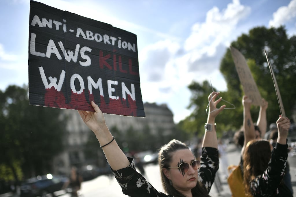 A protestor holds a sign and a hanger during a rally in support of worldwide abortion rights in Paris, after the US Supreme Court's overturned America's constitutional right to abortion, on June 24, 2022. (Photo by STEPHANE DE SAKUTIN / AFP) (Photo by STEPHANE DE SAKUTIN/AFP via Getty Images)