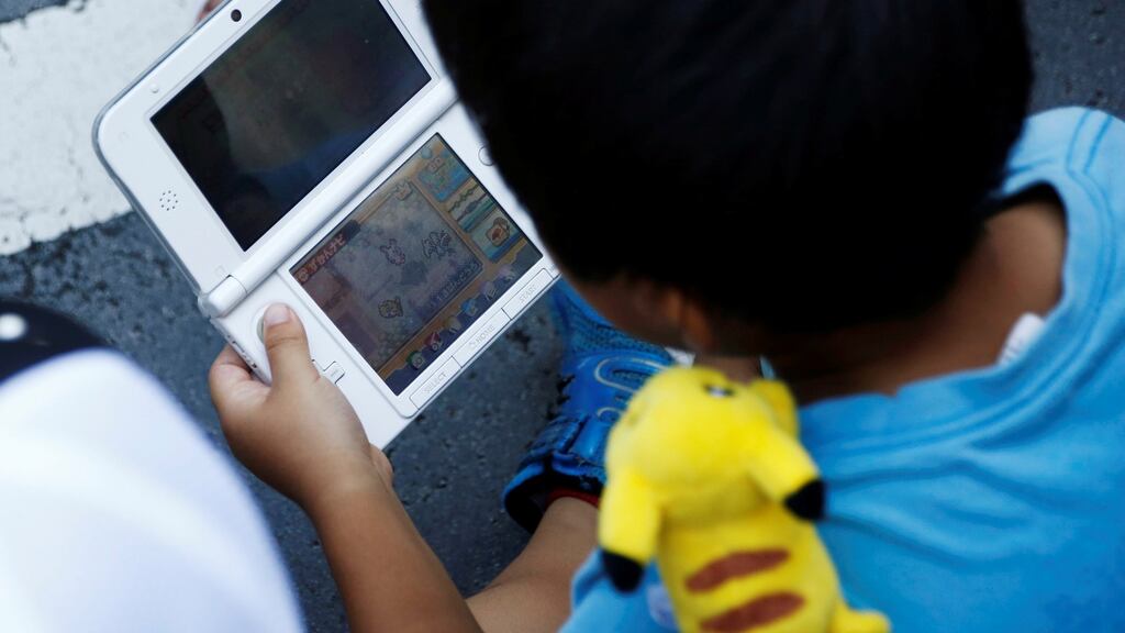 A boy plays Nintendo’s game console prior to a parade where Pokémon’s character Pikachu attends, in Yokohama, Japan. Photograph: Kim Kyung-Hoon/Reuters