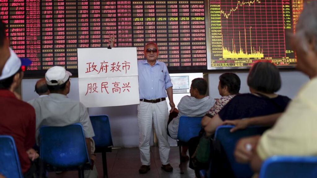 An investor holds a board showing “government saves the market so that investors will be happy” at a brokerage house in Shanghai, China. Photograph: Reuters/Aly Song