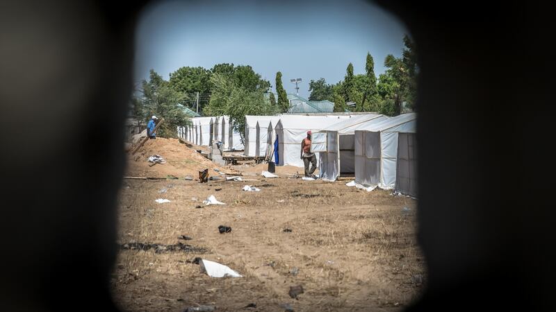 A view through a hole in a wall into Hajj camp, where so-called “repentant” Boko Haram fighters are being held. Journalists are not allowed to enter. Photograph: Sally Hayden.