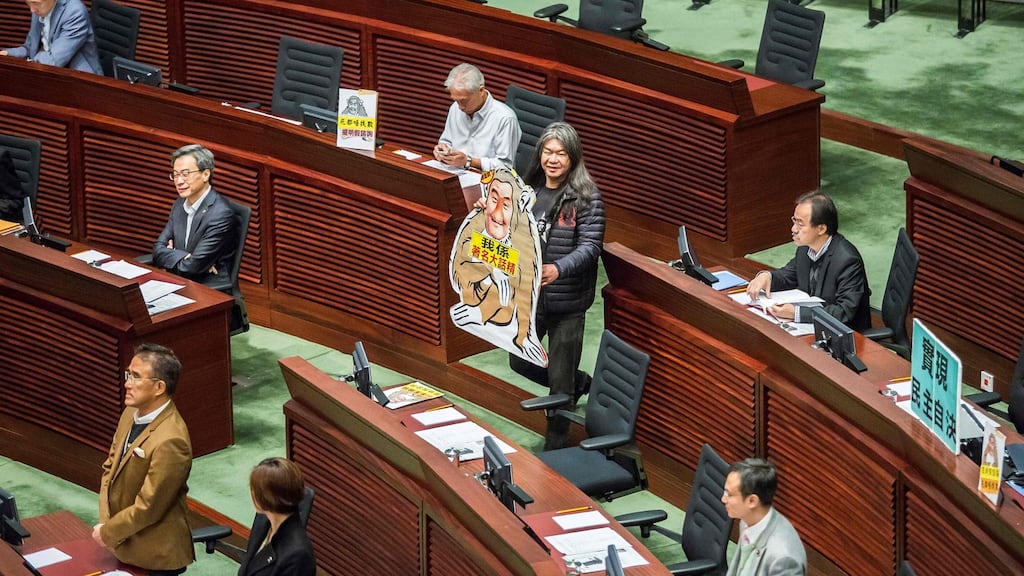 Leung Kwok-hung, known as “Long Hair”, brings a cut-out of a monkey bearing the likeness of Hong Kong’s chief executive CY Leung  into the chamber before Mr Leung’s final policy address to the legislative council on Wednesday. Photograph: Isaac Lawrence/AFP/Getty Images