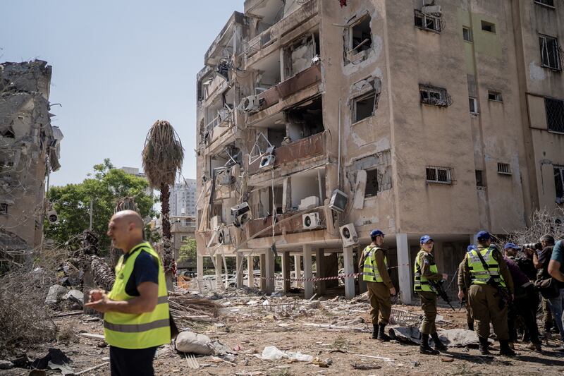 Israeli rescue team members survey damaged buildings in Holon. Photograph: Getty Images