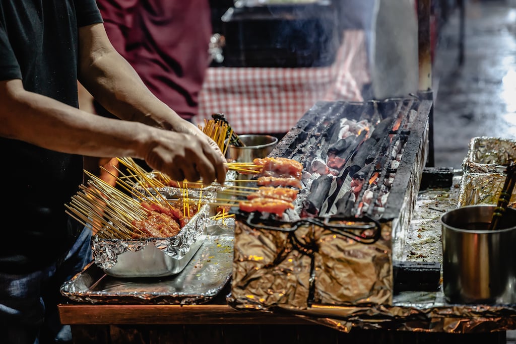 A grill and skewer expert at work on Lau Pa Sat hawker center's famous Satay Street. Singapore.