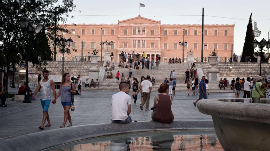 People sit outside the Greek parliament in Athens. Standard & Poor’s rating raised Greece’s credit rating by two notches to CCC+ after the indebted country reached a preliminary deal with its creditos for a third bailout deal. Photograph: AFP Photo