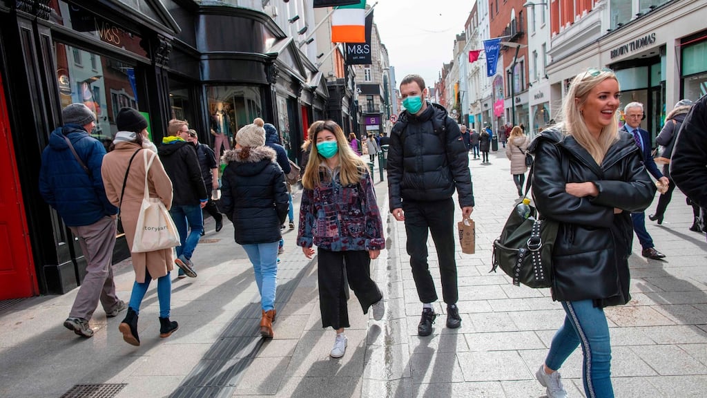 A couple wear surgical masks while shopping on Grafton Street, Dublin. The longer the health crisis continues the bigger the economic impact. Photograph: Paul Faith / AFP via Getty Images
