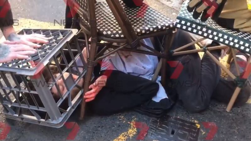 A man being restrained with the help of a milk crate and chairs by members of the public in Sydney. Photograph: Andrew Denney/7 News/PA Wire