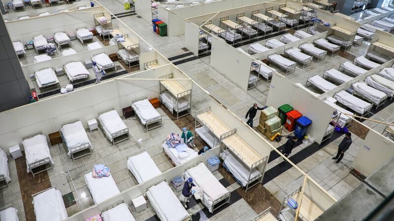 Medical staff members and workers setting up beds at an exhibition centre converted into a hospital in Wuhan. Photograph: STR/AFP via Getty Images