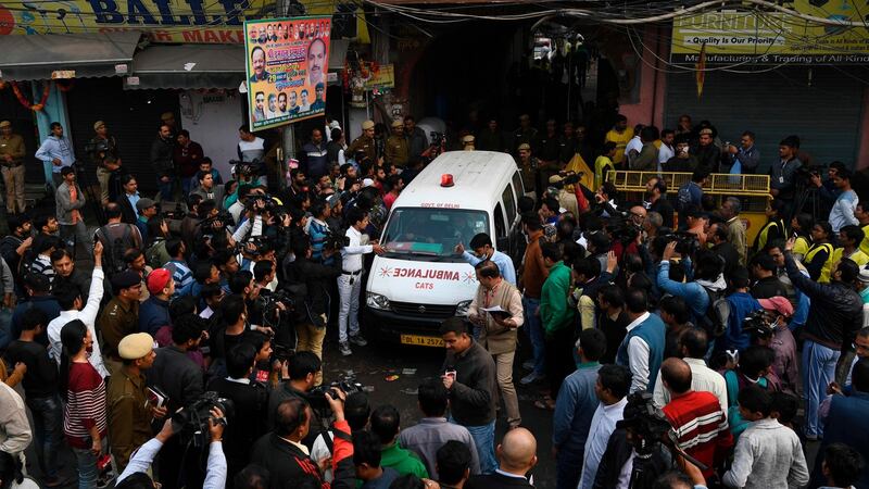 An ambulance surrounded by media drives out from a street leading to the factory site. Photograph: Sajjad Hussain/AFP/Getty Images
