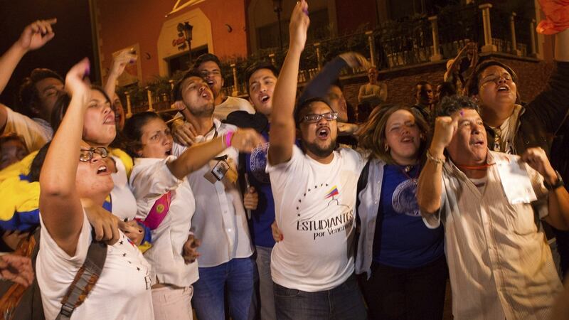 Several people celebrate in a street in Caracas, Venezuela, early on Monday, after the Venezuelan National Election Council’s president, Tibisay Lucena, announced that Venezuelan opposition coalition Mesa de Unidad Democratica (MUD) won the election. Photograph: EPA