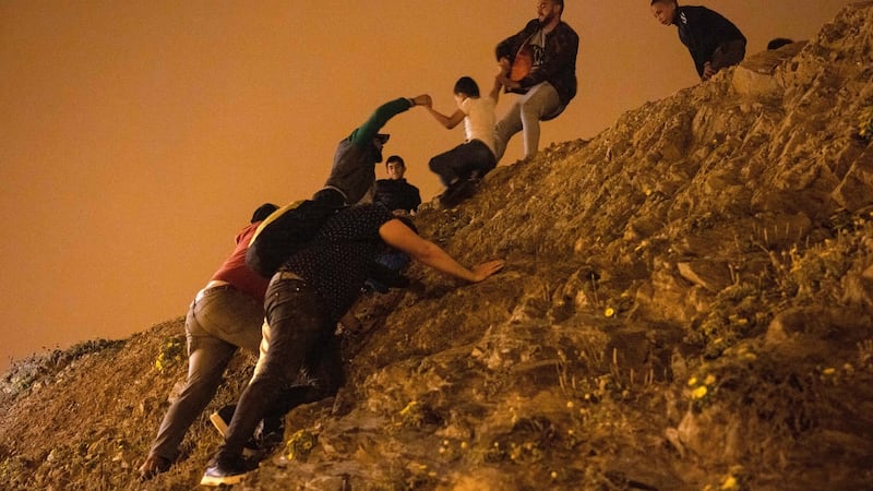 Moroccan migrants climb a rocky cliffside as they attempt to cross the border from Morocco to Spain’s north African enclave of Ceuta. Photograph: Fadel Senna/AFP via Getty Images)