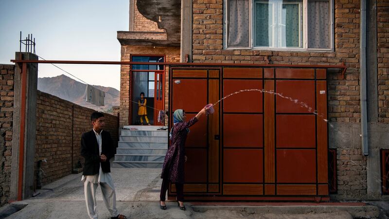 The sister and brother of Naiem Asadi throw water behind the family as they leave their house in Kabul; a tradition that is supposed to bring light to the path of a traveler and bring them home sooner on June 1st. Photograph: Kiana Hayeri/The New York Times