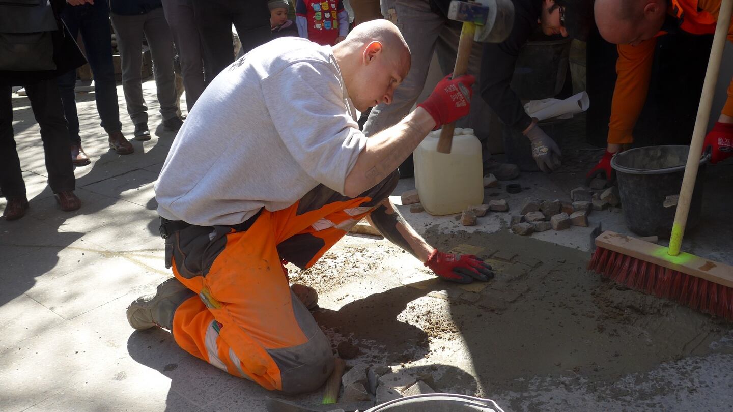 Memorial: a workman sets the Wyszniak Stoplersteine into the pavement on Bleibtreustrasse, in Berlin
