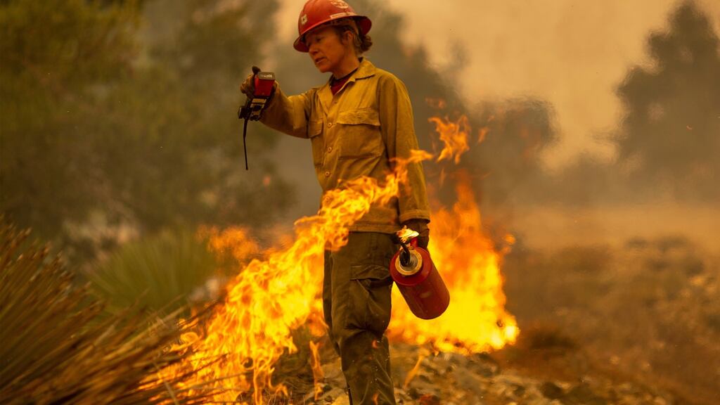 Mormon Lake Hotshots firefighter Sara Sweeney uses a drip torch to set a backfire to protect mountain communities from the Bobcat Fire in the Angeles National Forest in California. Photograph: David McNew/Getty Images