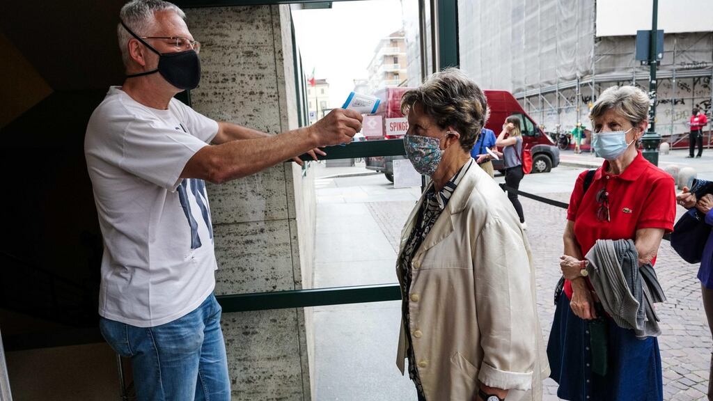 A staff member checks the temperature of a moviegoer wearing a face mask during the reopening of the Massimo cinema in Turin. Photograph:Tino Romano/EPA