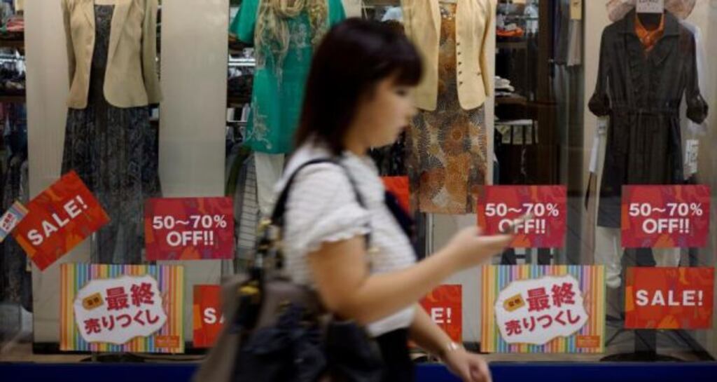 A woman passes a store in Tokyo. Household spending fell 5.9 per cent in July from a year earlier, new figures show.